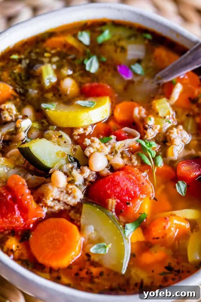 A beautiful white bowl filled with Homemade Turkey Vegetable Weight Loss Soup, with a spoon resting inside, showcasing its inviting texture.
