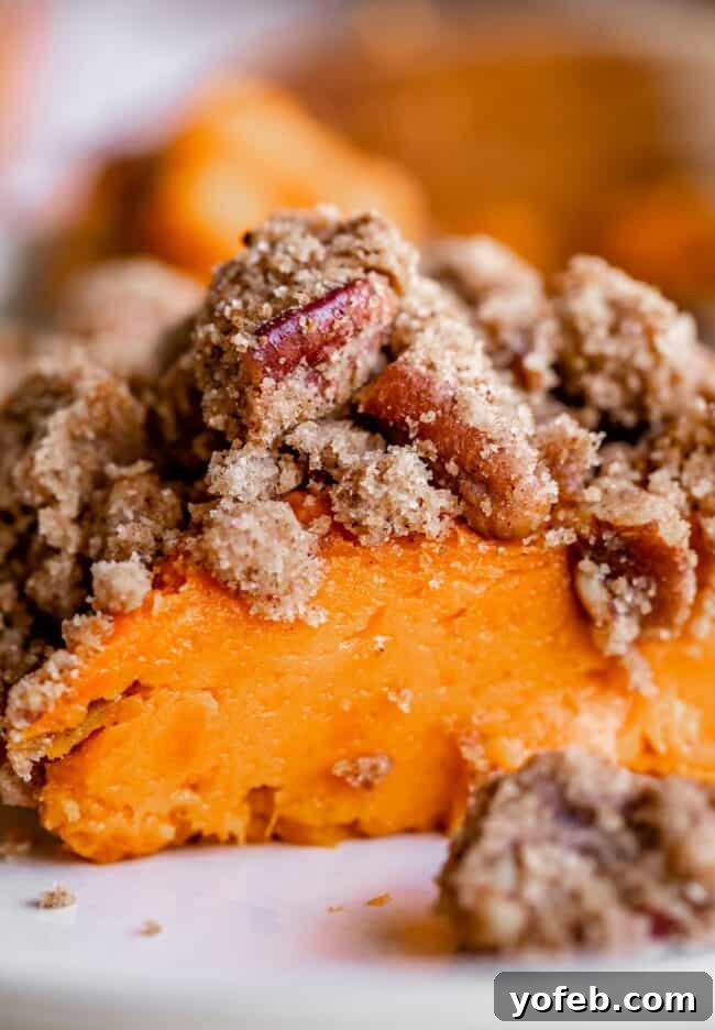 Heavenly Sweet Potato Crumble 6 A single serving of baked sweet potato casserole, scooped onto a white plate, revealing the golden streusel and tender sweet potato beneath.
