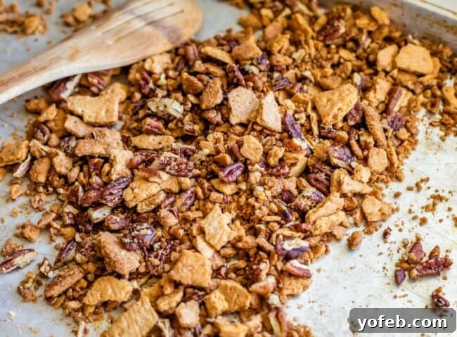 A baking sheet with buttered, toasted pecans and crushed graham crackers, ready to be baked into a crispy crumble.