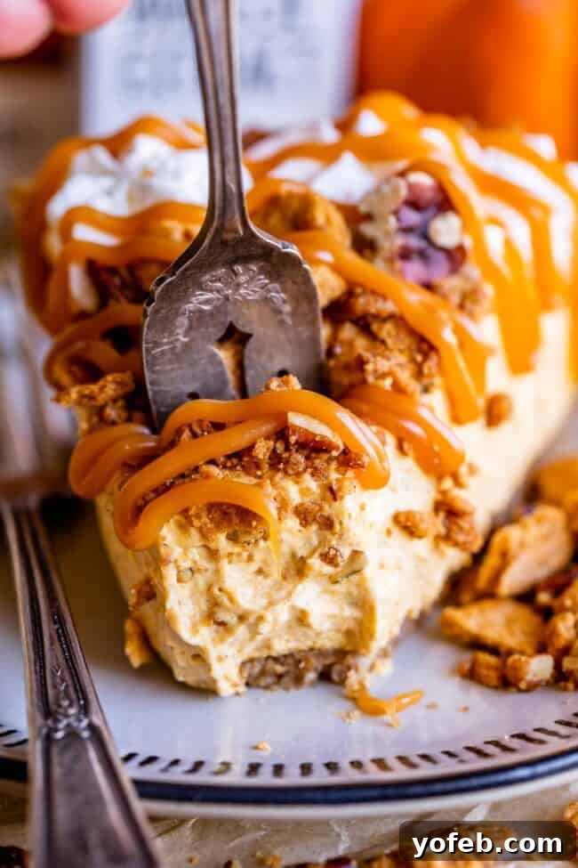 A fork cuts into a slice of easy no-bake pumpkin cheesecake, adorned with a luscious caramel drizzle, showcasing its tempting texture.