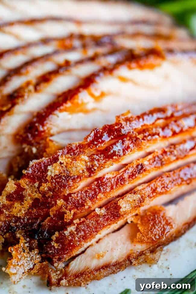 Ultimate Honey Baked Ham 2 Sliced honey baked ham on a plate, showcasing its glistening glaze and crispy edges.
