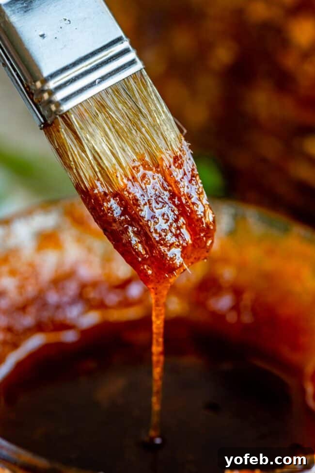 Ultimate Honey Baked Ham 13 Honey baked ham glaze dripping from a pastry brush, ready to be served.