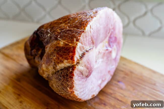 Ultimate Honey Baked Ham 6 Half a spiral ham displayed on a cutting board, ready for preparation.