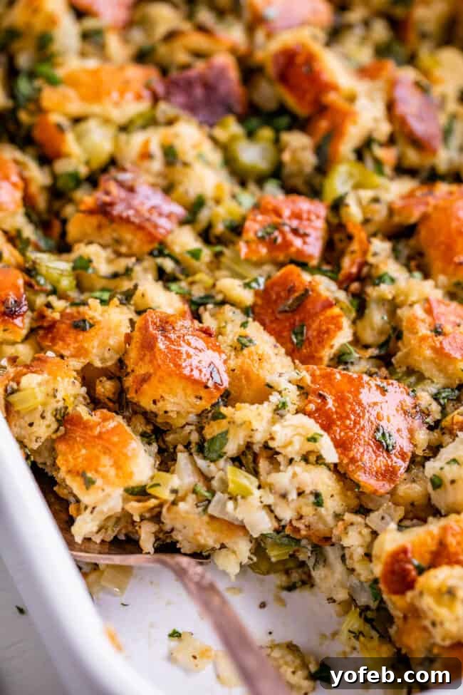 The Ultimate Thanksgiving Stuffing 21 best stuffing recipe in a white dish from the side with a spoon