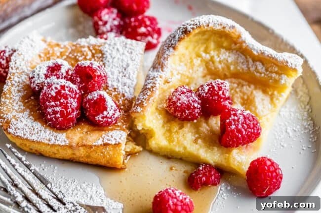 two pieces of German pancakes on a plate with raspberries.