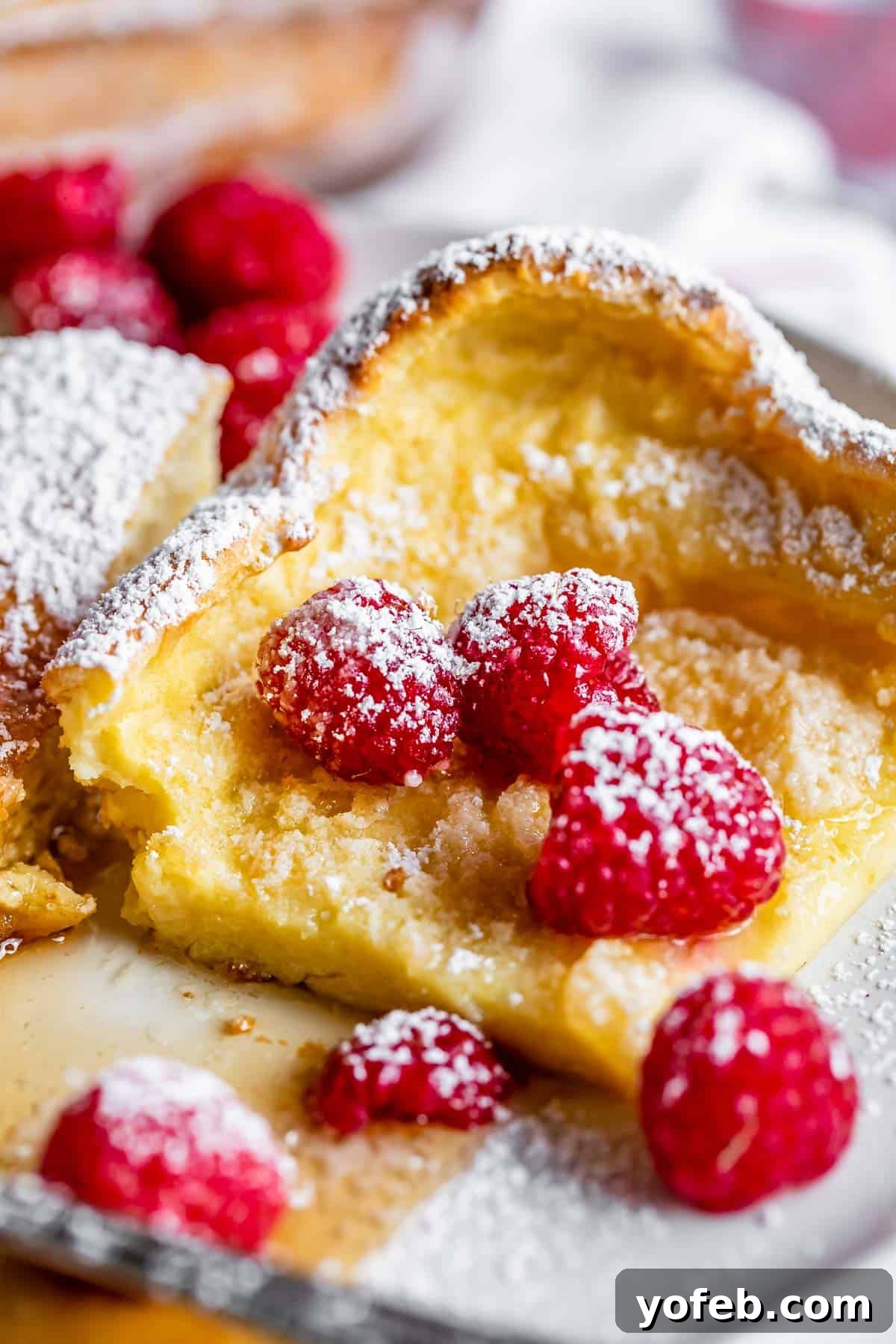 German pancake recipe with raspberries, syrup, and powdered sugar