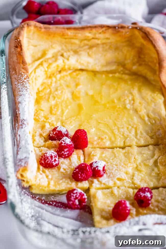 puffy pancakes in a 9x13 pan with raspberries and powdered sugar.