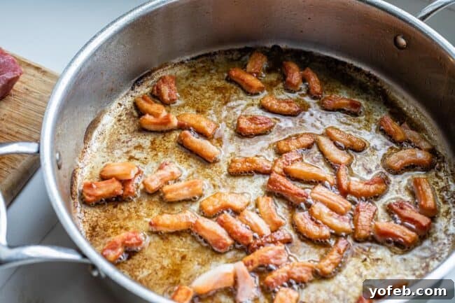 Classic French Beef Bourguignon 16 Crispy, golden-brown salt pork frying in a pan, rendering its fat to create a flavorful base for the Beef Bourguignon.