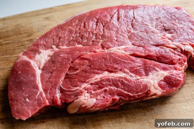 Classic French Beef Bourguignon 9 A well-marbled slab of chuck roast rests on a cutting board, displaying its rich color and readiness for preparation.