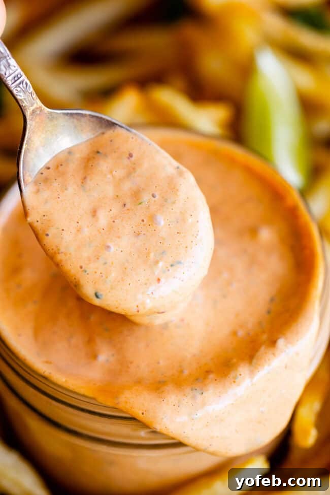Whip Up Your Own Smoky Chipotle Sauce 3 A spoon lifting rich, creamy homemade chipotle mayo from a glass jar.