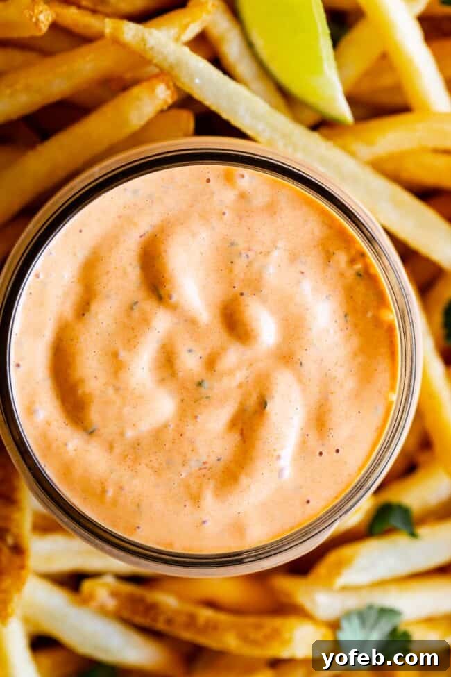 Whip Up Your Own Smoky Chipotle Sauce 4 Close-up of chipotle mayo sauce in a mason jar, surrounded by golden french fries and fresh lime slices.