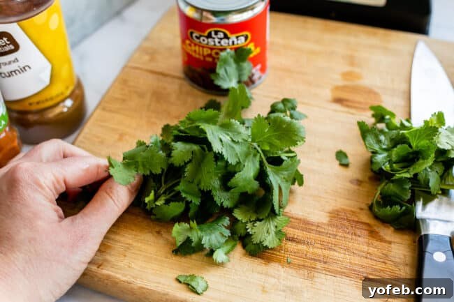 Whip Up Your Own Smoky Chipotle Sauce 11 Fresh cilantro on a wooden cutting board with a knife, ready for chopping.