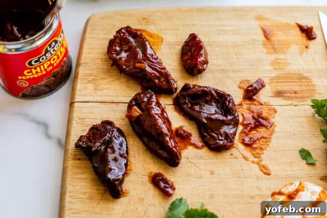 Whip Up Your Own Smoky Chipotle Sauce 9 Whole chipotle peppers laid out on a wooden cutting board, showing their varying sizes.