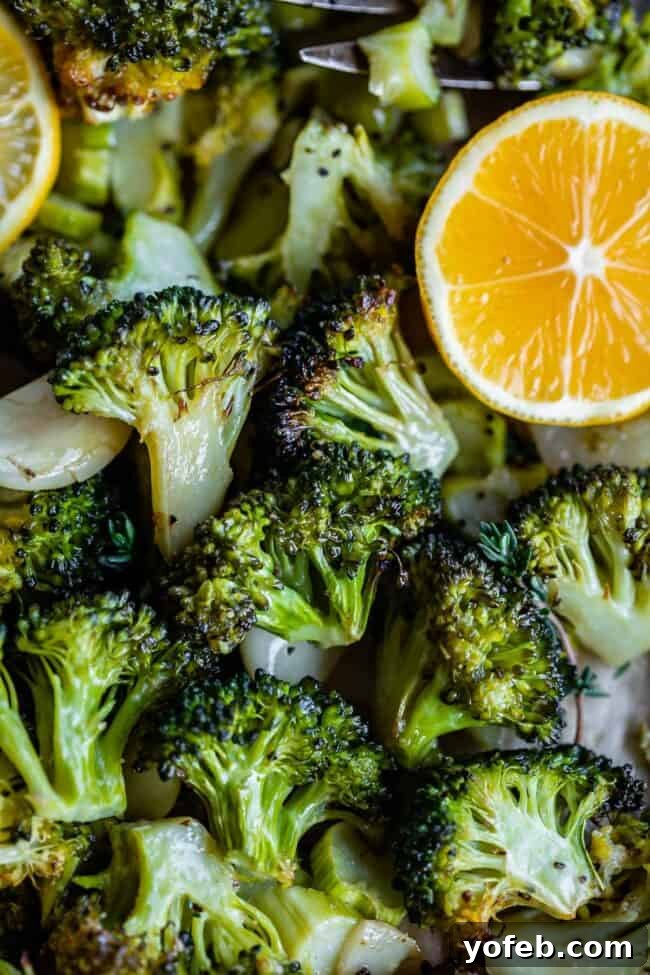 A vibrant bowl of oven-roasted broccoli, perfectly charred and seasoned with visible garlic and a fresh lemon wedge, ready to be served as a healthy and flavorful side dish.