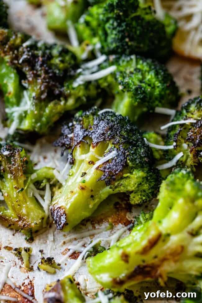 A vibrant bowl of garlic roasted broccoli, generously sprinkled with freshly grated Parmesan cheese, showcasing its appealing golden-brown edges and delicious texture.