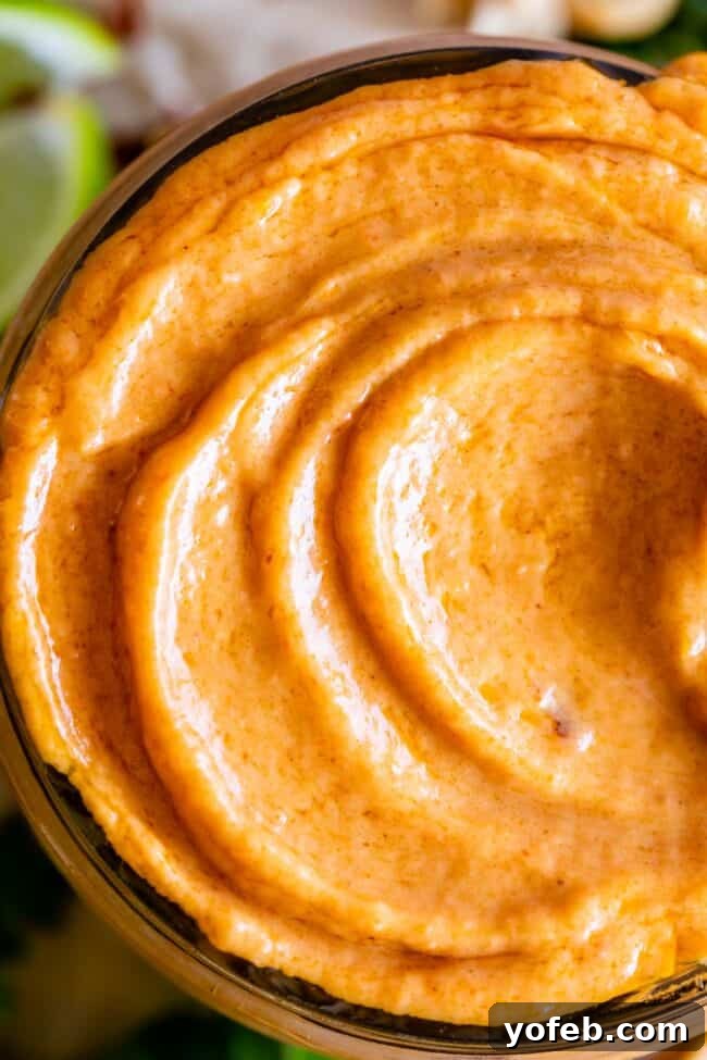 Effortless Homemade Peanut Sauce 4 A close-up, overhead shot of a glass jar filled with luscious Thai peanut sauce, featuring delicate swirls on its surface that suggest its creamy texture and rich flavor.