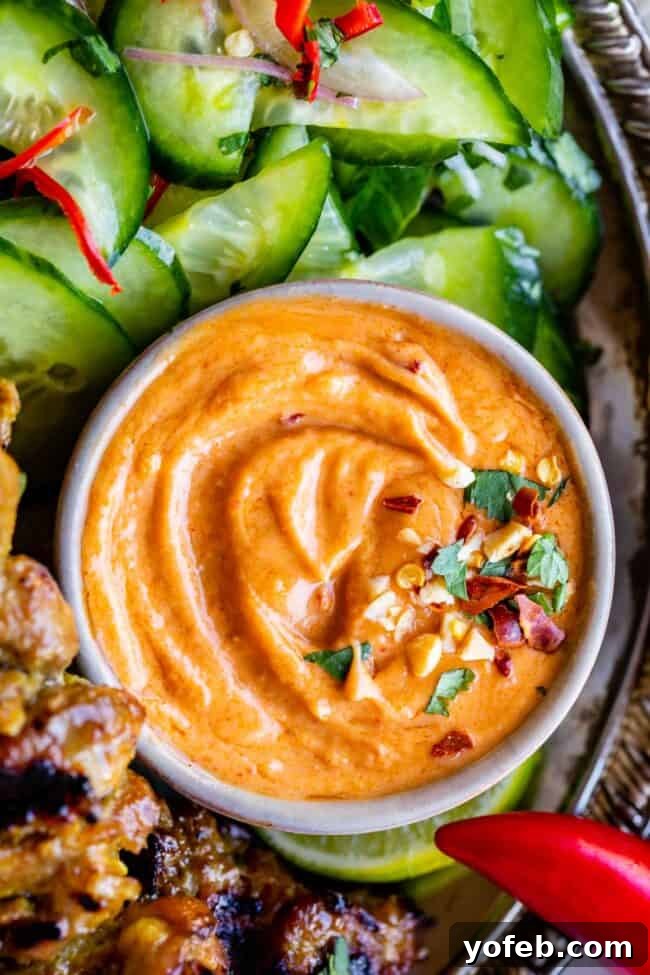 Effortless Homemade Peanut Sauce 7 A beautifully presented dish featuring easy Thai peanut sauce in a small bowl, accompanied by a refreshing cucumber salad and grilled satay skewers on the side, creating a complete and inviting meal.