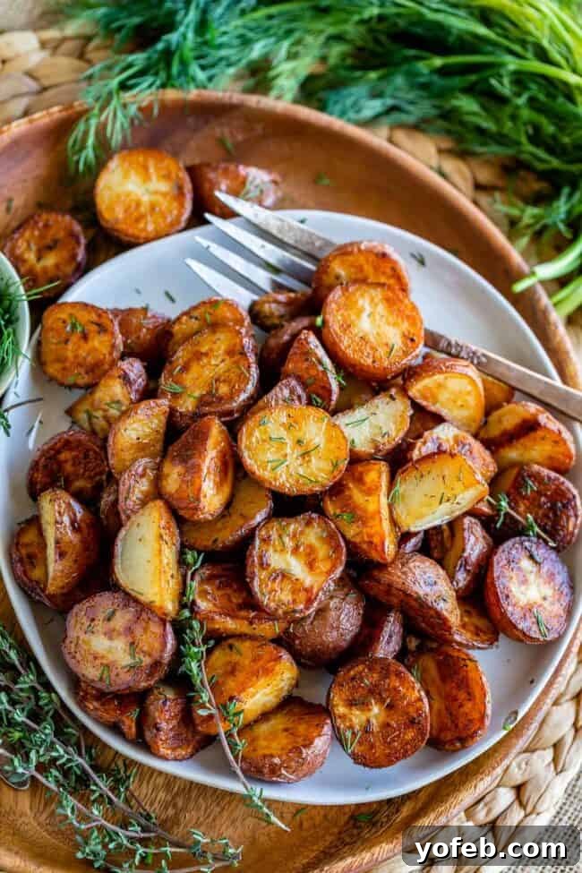 Crispy Oven-Roasted Red Potatoes 3 white plate with oven roasted red potatoes garnished with fresh dill on a wooden background, creating a rustic feel