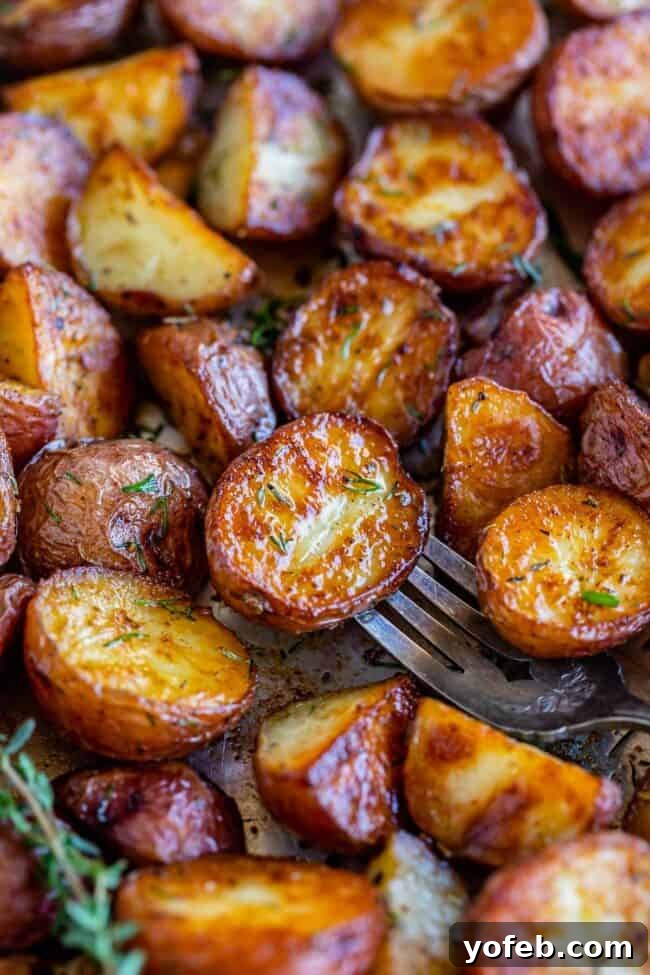 Crispy Oven-Roasted Red Potatoes 6 garlic roasted red potatoes with fresh herbs on a baking sheet, with a serving fork, ready to be enjoyed