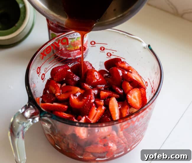 Adding cooked jam to a bowl of freshly sliced strawberries.