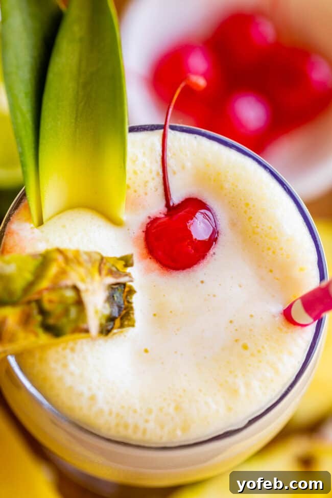Island Oasis Piña Colada 2 A frosty virgin piña colada, garnished with fresh pineapple slices, a vibrant maraschino cherry, and a colorful straw, ready to be enjoyed.