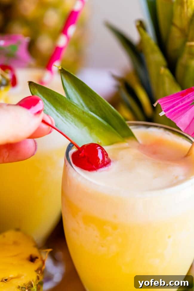 Island Oasis Piña Colada 10 Two beautiful virgin piña coladas served in elegant goblets, each garnished with a bright cherry, highlighting their inviting appearance.