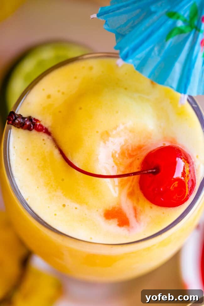 Island Oasis Piña Colada 18 A close-up shot of a pristine virgin piña colada, beautifully garnished with a maraschino cherry and a mini umbrella, inviting a refreshing sip.