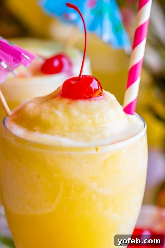 Island Oasis Piña Colada 4 A single virgin piña colada presented beautifully with a cherry, a striped straw, and a charming mini umbrella, ready to be enjoyed.