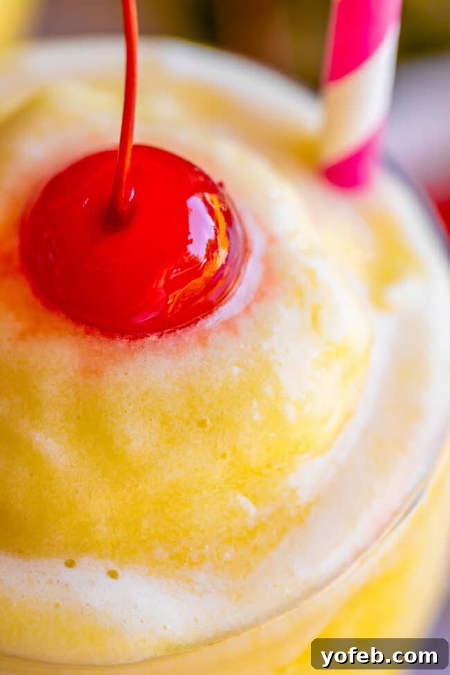 Island Oasis Piña Colada 5 A vibrant close-up of a virgin piña colada, showcasing its creamy texture and topped with a bright red maraschino cherry.