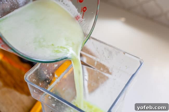 Creamy Brazilian Lemonade Recipe 14 The strained limeade liquid being poured back into a blender, preparing for the final frothing step with sweetened condensed milk.
