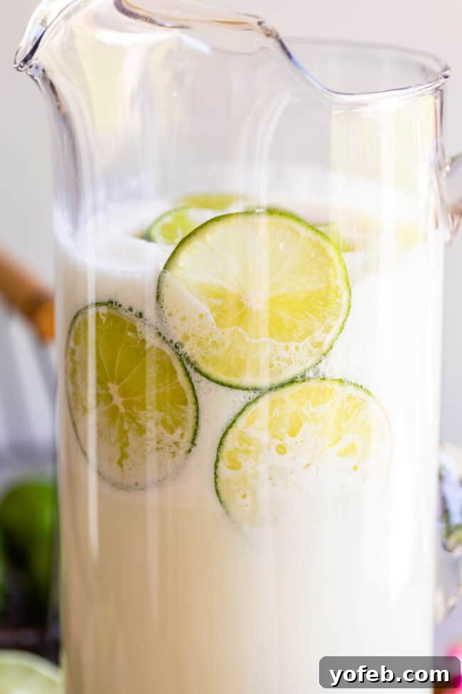 Creamy Brazilian Lemonade Recipe 4 A pitcher of vibrant Brazilian Lemonade, surrounded by fresh lime slices, inviting a cool, tart sip.