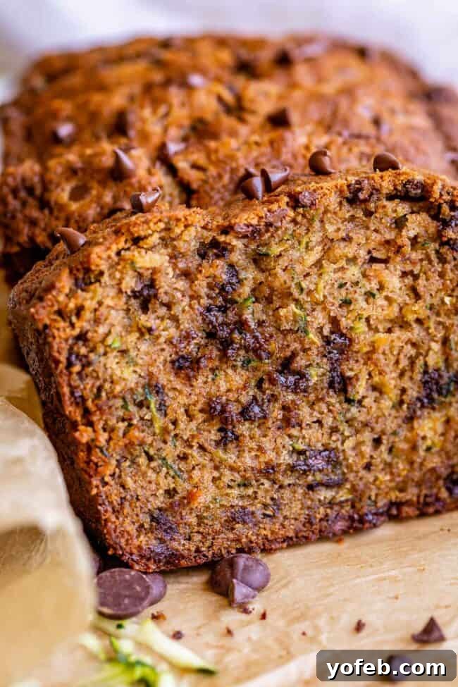 Heavenly Zucchini Bread 7 closeup of a slice of moist zucchini bread with a full loaf in the background.