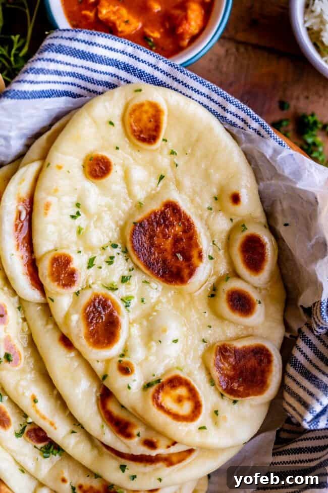 buttery naan with fresh parsley, stacked on a blue and white striped napkin.
