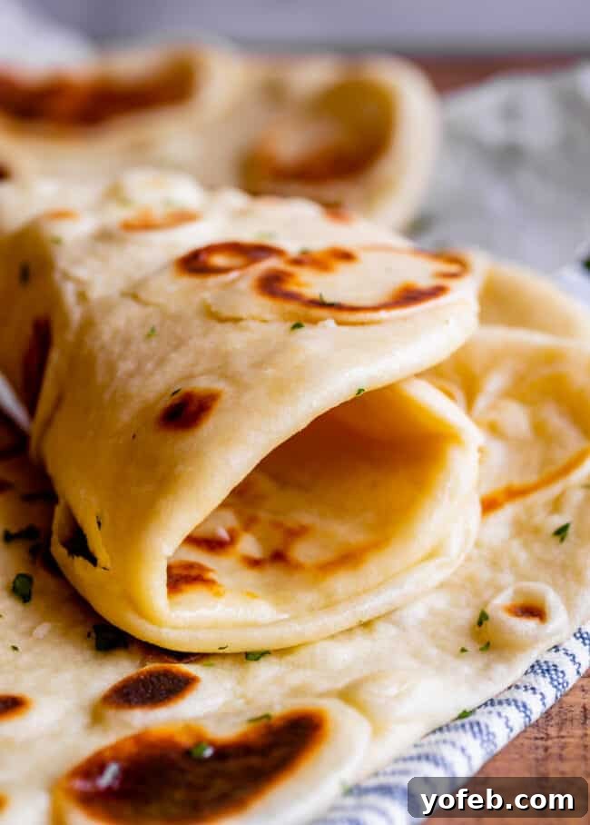 homemade naan bread rolled up on a blue and white striped towel.