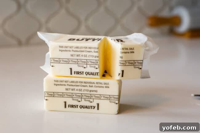 Dreamy White Chocolate Chip Treats 11 stick of butter on a counter with another stick on top cut in half