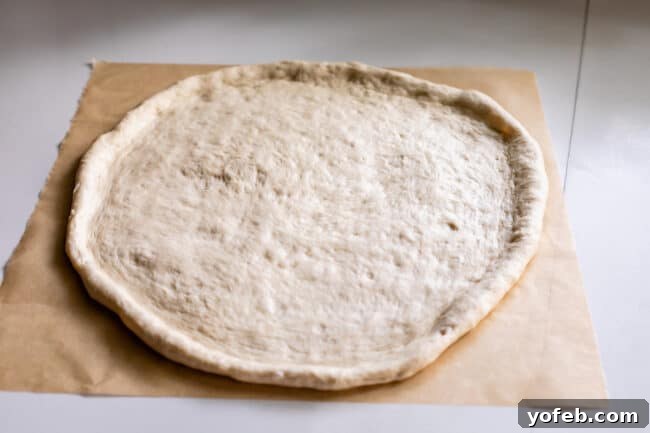 The Ultimate Homemade Pizza Ready When You Are 13 Pizza dough, perfectly rolled out and placed on a sheet of parchment paper, ready for toppings.