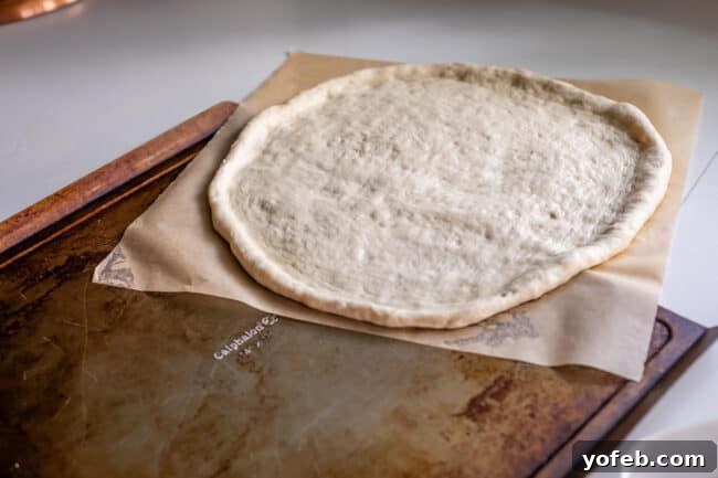 The Ultimate Homemade Pizza Ready When You Are 15 Transferring raw pizza dough, along with parchment paper, onto a flat baking sheet before par-baking.