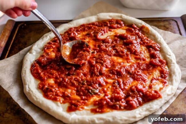 The Ultimate Homemade Pizza Ready When You Are 17 Spreading a rich red pizza sauce evenly over a par-baked pizza dough.
