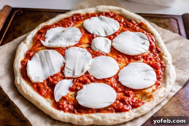 The Ultimate Homemade Pizza Ready When You Are 19 Slices of mozzarella cheese arranged on a raw pizza base, preparing for baking.