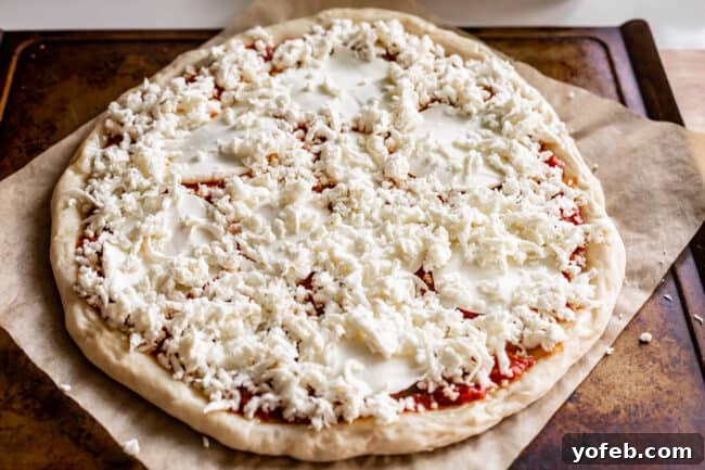 The Ultimate Homemade Pizza Ready When You Are 20 Raw pizza dough topped with a layer of sliced and shredded mozzarella cheese, ready for additional toppings.