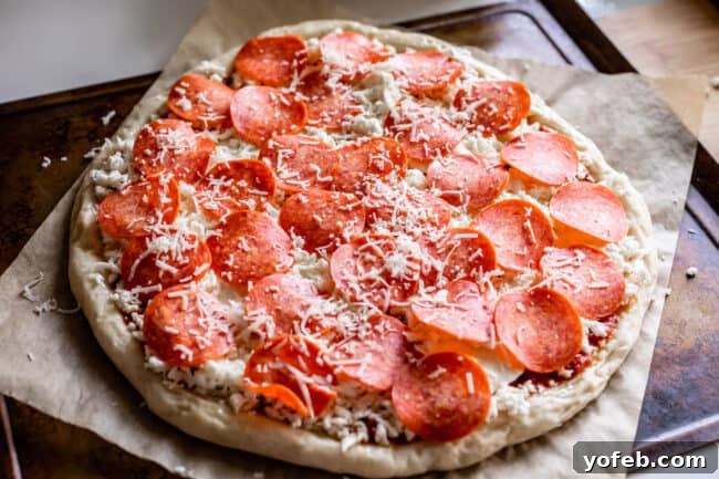 The Ultimate Homemade Pizza Ready When You Are 22 Rolled out pizza dough topped with sauce, cheese, and pepperoni, ready for the oven.