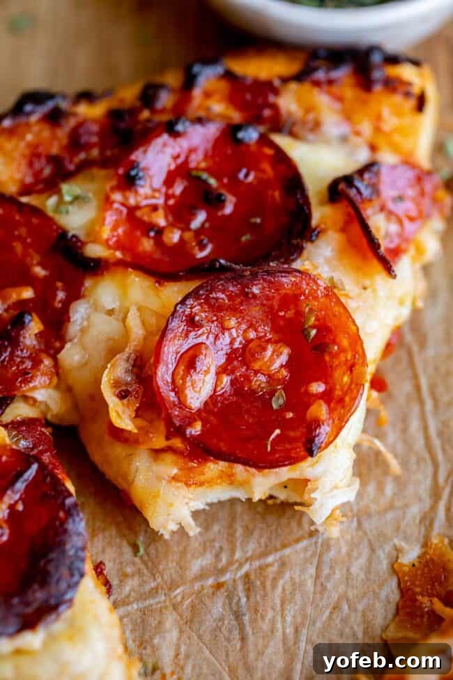 The Ultimate Homemade Pizza Ready When You Are 8 A bite taken out of a delicious slice of homemade pizza, showing the texture of the crust and melted cheese.
