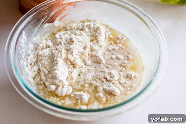 Foolproof Pizza Dough for Newbies 13 flour added to a bowl of yeast and water.