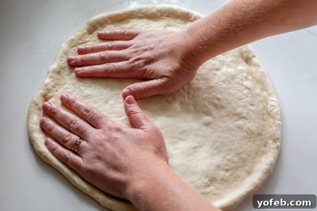 Foolproof Pizza Dough for Newbies 20 two hands spreading out and stretching pizza dough.