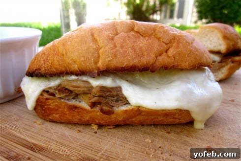 Ultimate Slow Cooker French Dip Sandwiches 27 Original French dip sandwich photo from 2012 on a cutting board with melted cheese, showcasing its timeless appeal.