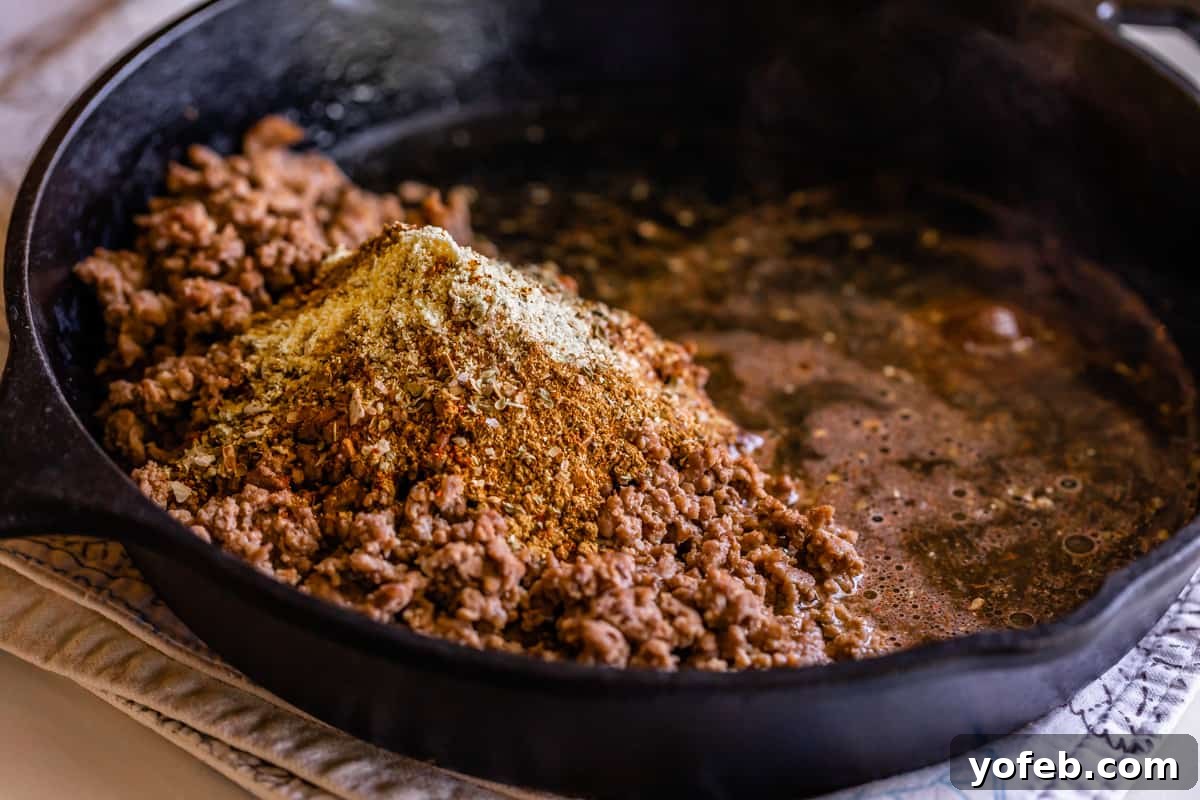 Elevate Your Tacos with Homemade Seasoning 12 Adding homemade taco seasoning to crumbled ground beef in a cast iron skillet.