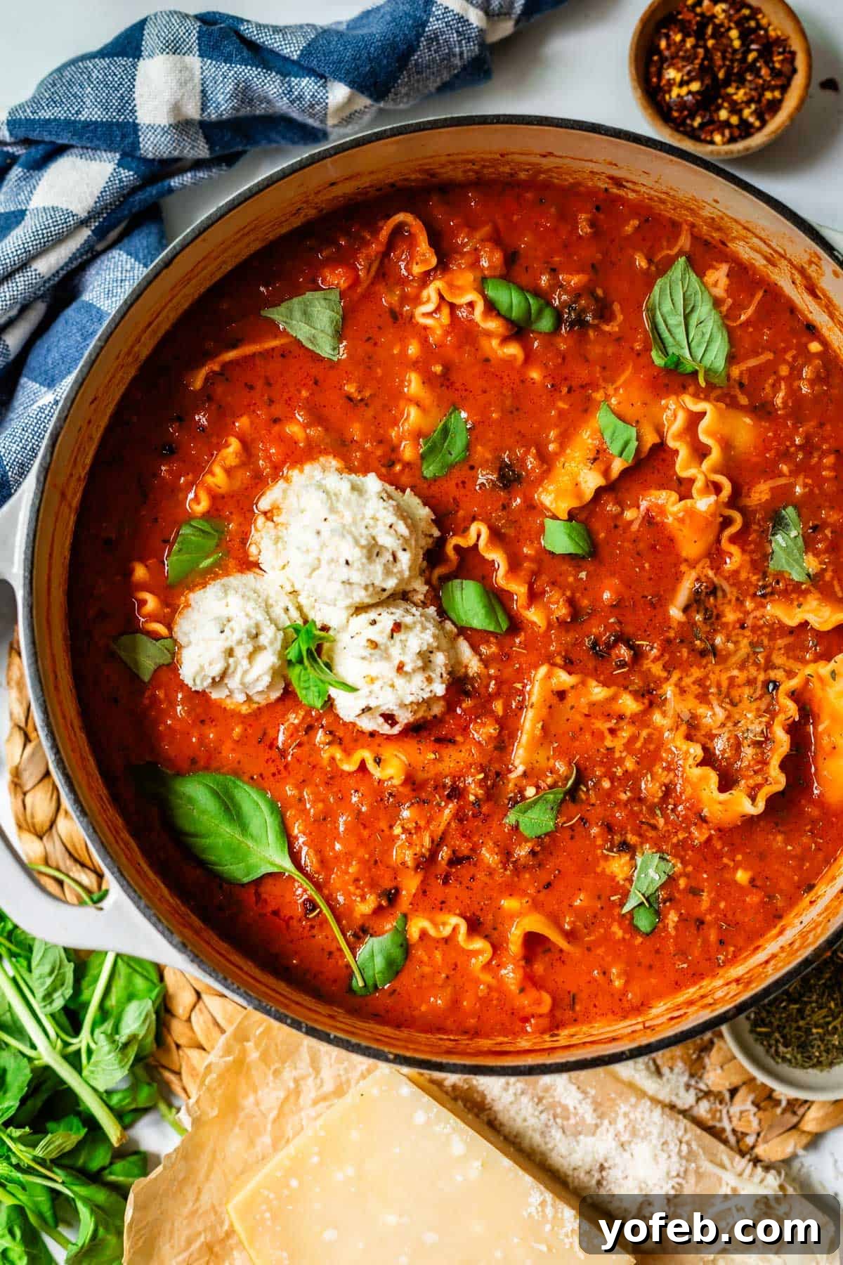 The Definitive Lasagna Soup 19 A large pot of homemade lasagna soup sits on a counter, with fresh basil and chili flakes beside it for garnish.
