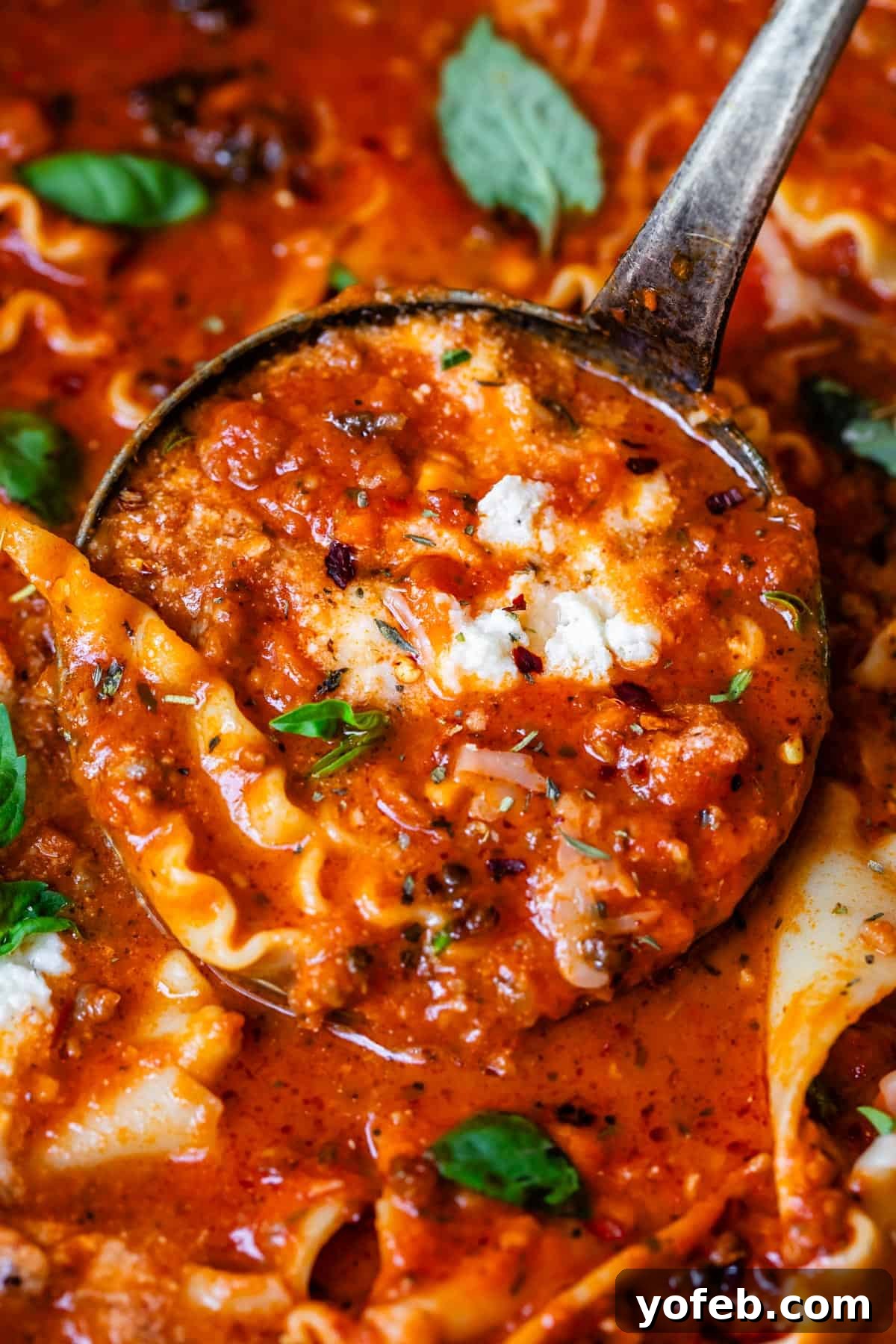 The Definitive Lasagna Soup 5 A metal ladle scooping a generous portion of lasagna soup, showcasing the rich broth and noodles.