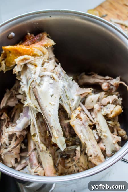 Homemade Turkey Stock: Carcass in Pot. Learn how easy it is to make Turkey Stock from the bones of your Thanksgiving turkey! All you need is a picked over turkey carcass and some vegetables and herbs that you probably already have on hand from cooking your turkey. You are going to love using this flavorful turkey stock in your next soup! #turkey #stock #fromcarcass #recipe #forgravy #uses #fromneckandgiblets #homemade #slowcooker #crockpot #soup #howtomake #leftovers turkey carcass inside pot for turkey bone broth recipe.