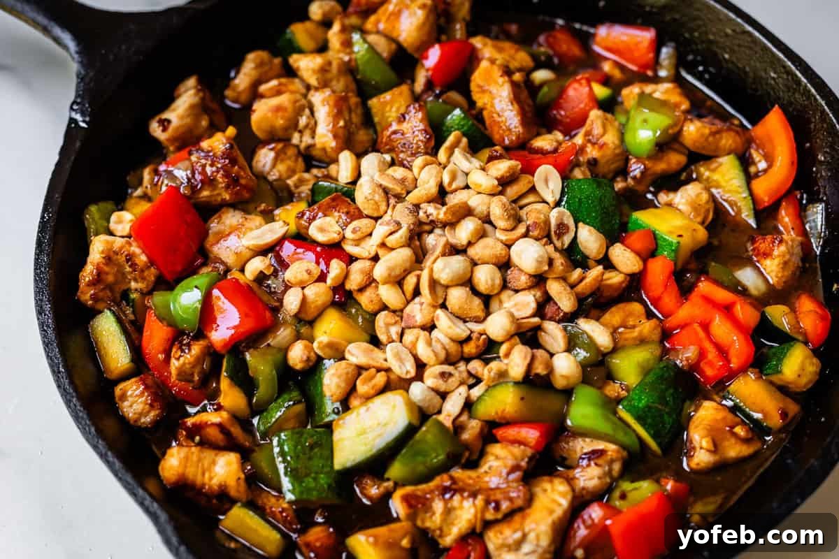 Szechuan Kung Pao Chicken 16 A cast iron skillet filled with perfectly cooked Kung Pao chicken, generously topped with roasted peanuts, ready to be served.